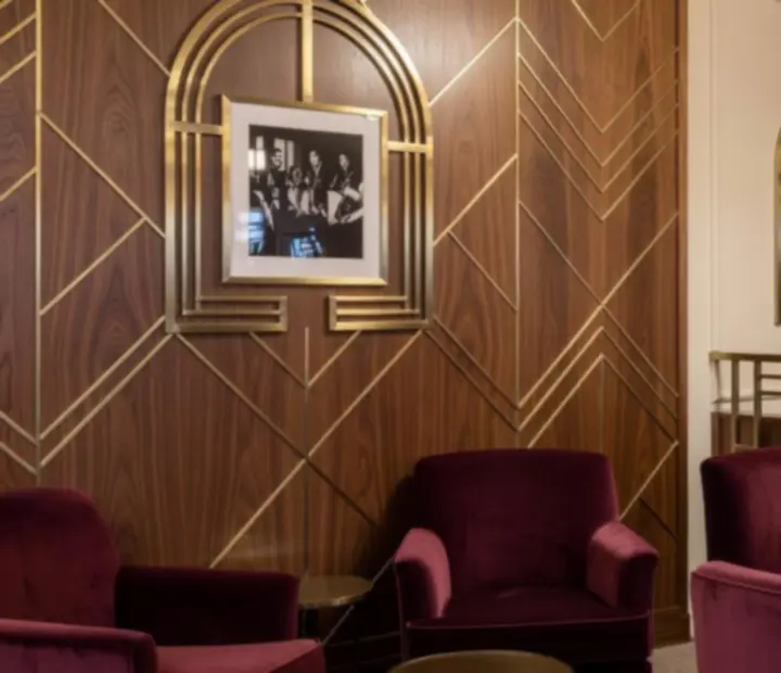Detale Art Deco w Lounge Casino Brav Qelia z mosiężnymi lampami i bordowymi akcentami