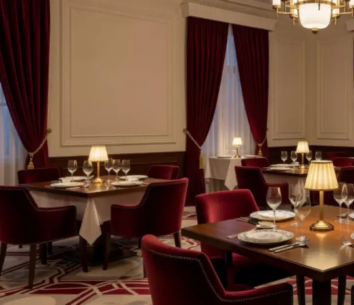 Sala główna restauracji Czerwony Stół z kremowymi ścianami, mosiężnymi lampami i burgundowymi fotelami.