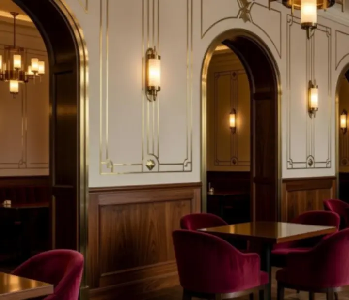 Eleganckie polskie wnętrze restauracji w stylu art deco z kremowymi ścianami, mosiężnymi lampami i łukowymi przejściami.